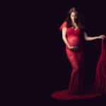 צילומי הריון להילה שמחזיקה שובל שמלה אדומה תחרה