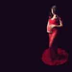 צילומי הריון להילה בשמלה אדומה מתחרה על רקע שחור