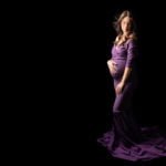 צילום הריון להילה בשמלה סגולה על רקע שחור