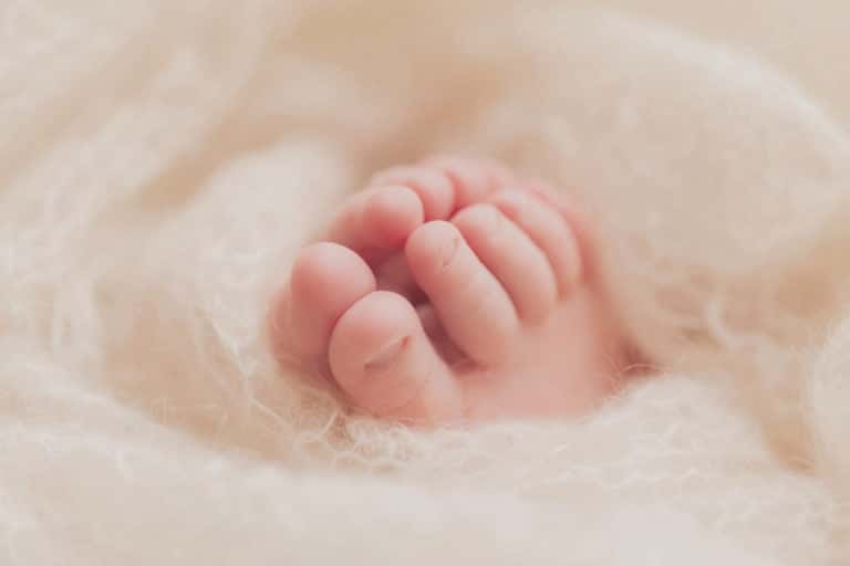 כפות רגליים קטנטנות של תינוקת בת שבוע בזמן צילומי ניובורן