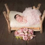 תינוקת בת שבוע ישנה במיטה מעץ בזמן צילומי ניובורן