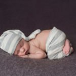צילום ניובורן לתינוק עם מכנס אפור וכובע אפור