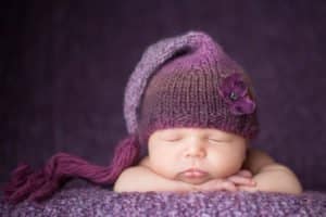 תמונה של תינוקת על רקע סגול עם כובע סגול בצילום ניו בורן