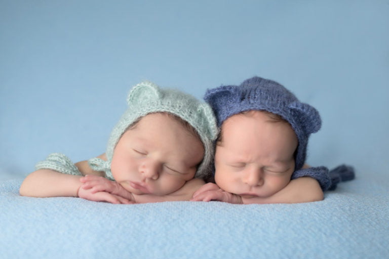 צילומי ניובורן לתאומים בשילוב כובעים תואמים על רקע תכלת
