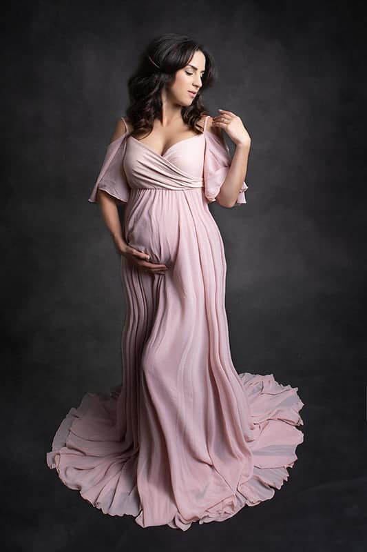 צילום הריון לאתי בשמלה ורודה על רקע אפור